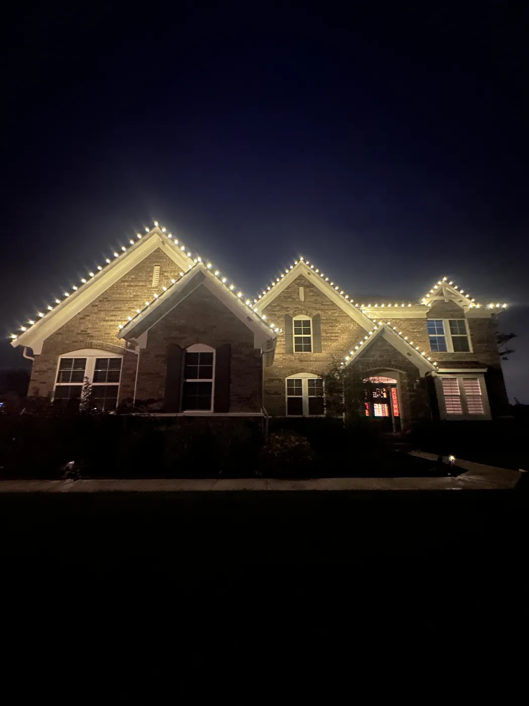 Home outlined in warm holiday lights at night