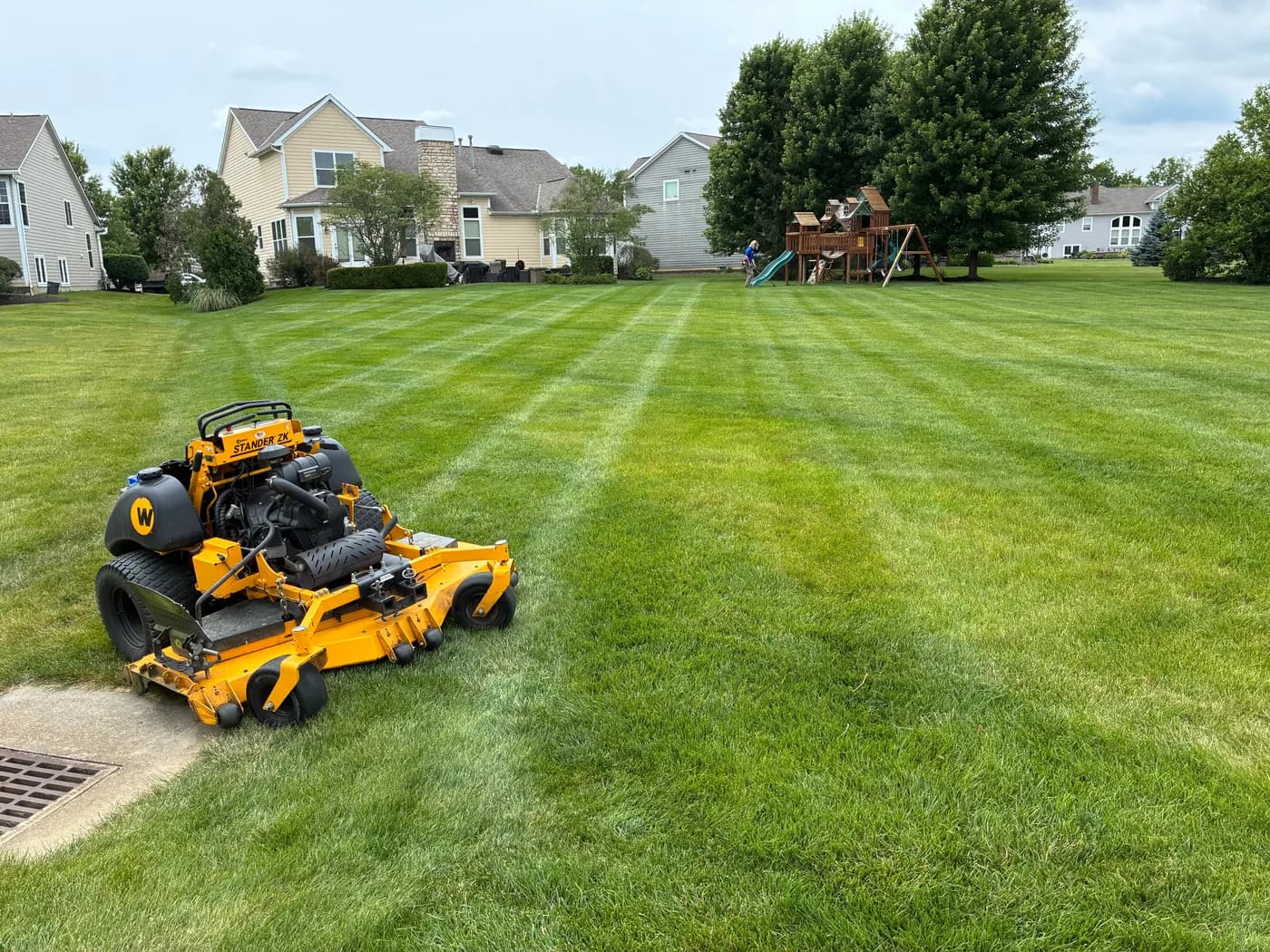 Stand-on mower beside a freshly striped lawn