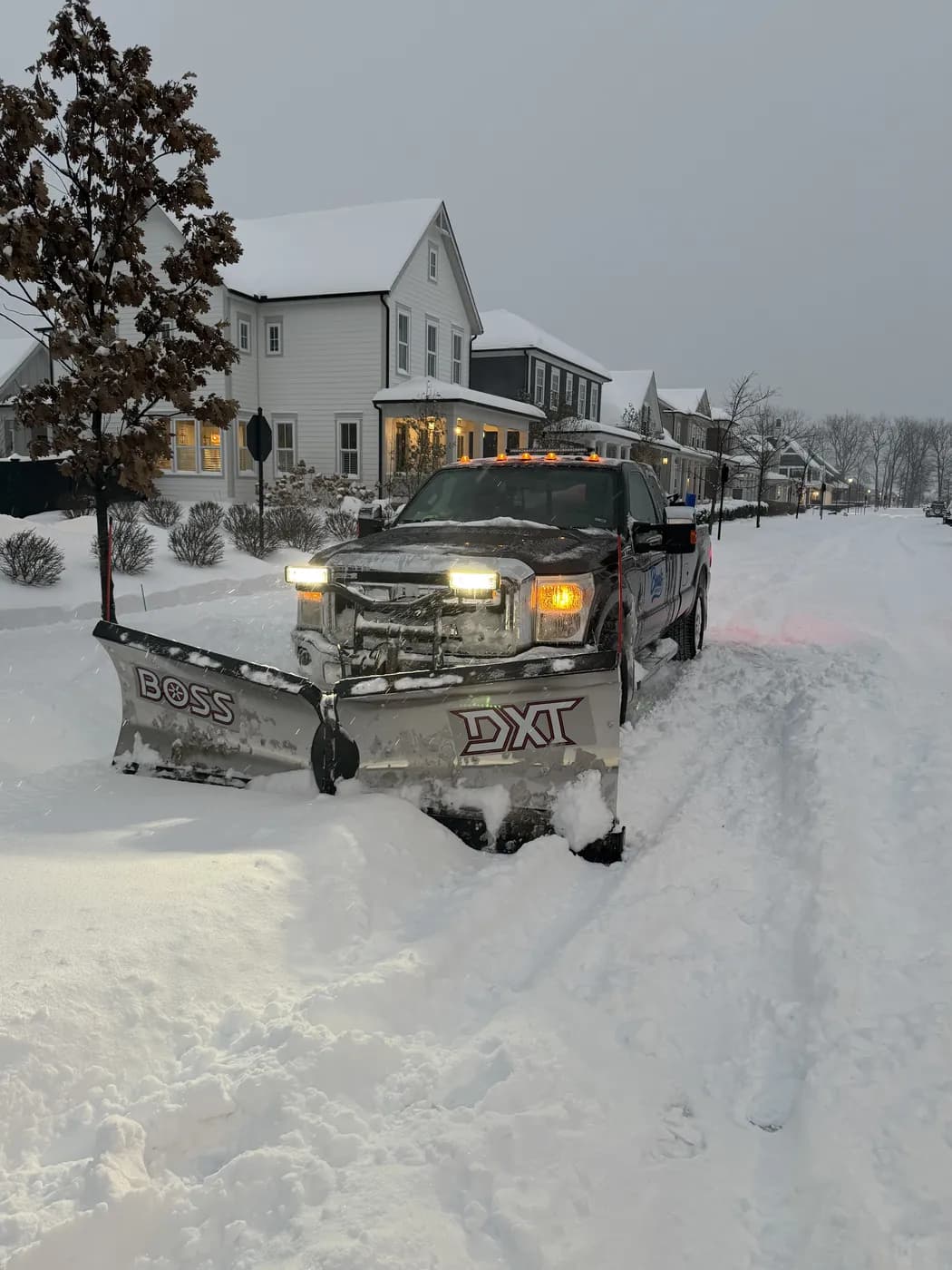 Plow truck clearing deep snow on a neighborhood street